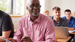 Mature Student Using Digital Tablet In Adult Education Class