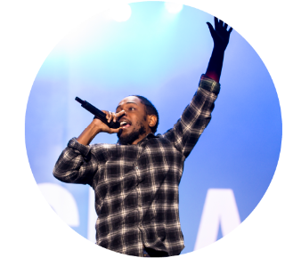 Kendrick Lemar Kendrick Lemar onstage, holding a microphone to his mouth and holding his other hand in the air.