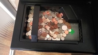 A coin deposit machine. in a bank branch with coins in.