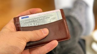 LONDON - APRIL 15, 2018: A man holds a leather wallet containing an American Express credit card in London, UK.