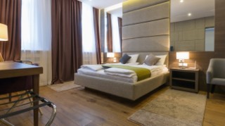 Hotel room with a double bed and brown, beige and wood furnishings.