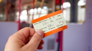 Left hand holding up a National Rail ticket.