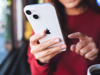 Close up photograph of a young woman using a white Apple iPhone 13.