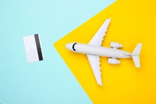 Flat lay travel composition. Airplane figurine, bank card on color paper background. Purchase and reservation of air tickets, payment for rest. Top view
