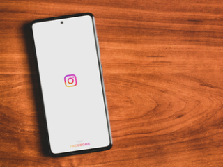 Instagram on a smartphone Smartphone displaying the opening screen on Instagram laying on a wooden surface.