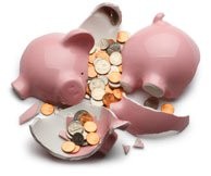 Pink piggy bank broken into several pieces with various coins spilling out of it.