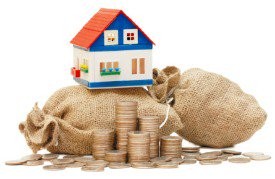 Model house sitting on top of two sacks of money, with coins piled in front of them.