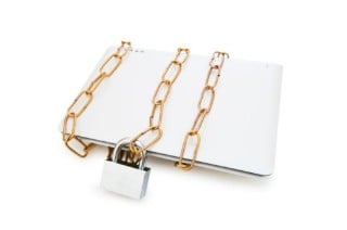 A white laptop with a gold chain around it, locked with a silver padlock.