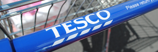 Close up of the Tesco logo on the handle of a shopping trolley. 