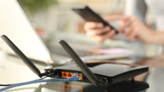 Close up of woman hands using multiple devices with broadband router on foreground