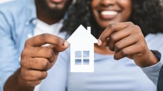 Real estate, housing and family concept. Close up of black couple holding wooden house