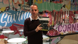 Martin Lewis facing camera and holding copy of financial education textbook