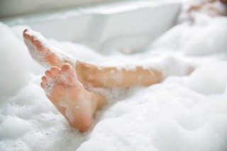 Feet sticking out of a cloud of bubbles in a bathtub