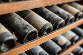 Dusty bottles of wine in a wooden wine holder