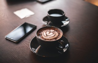 Two cups of hot chocolate and a mobile phone on a table