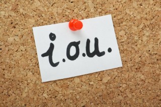 An 'I O U' note pinned to a corkboard