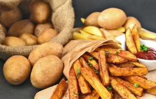 A sack of potatoes, some chips wrapped in brown paper and a ramekin of ketchup