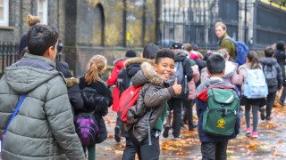 primary asian, Indian, Chinese   Caucasian student or kids carrying  school bag on their way to visit British museum, City of Westminster, London in rain winter day, with maple leaves on ground