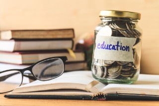 A jar containing coins with "education" written on the side on a label. A jar containing coins with "education" written on the side on a label.